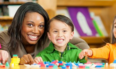 Teacher smiling with three preschoolers